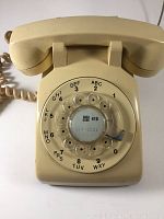 Front view of beige Northern Electric rotary dial telephone showing dial with area code 416 and coiled cord.