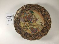 Single Satsuma decorative plate with floral and bird scene, measuring 10 inches diameter, with ornate gold and multicolor pattern, no visible cracks or chips, slight crazing visible on surface.