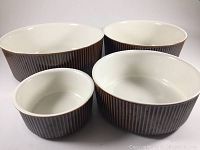 Set of four souffle casserole dishes showing overall group with chocolate brown ribbed exterior and cream interior.