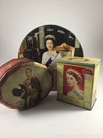Three British monarchy commemorative tins shown together: round 1977 Silver Jubilee tin with Queen Elizabeth II portrait, rectangular 1952 coronation sweets tin with Queen Elizabeth II portrait, and hexagonal King Edward VII hinged tin with vintage portrait.