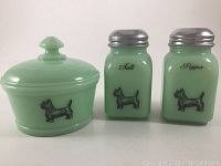 Front view of set showing green milk glass salt and pepper shakers with metal lids and covered sugar bowl, each decorated with Scotty dog motif.