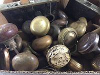 Box with assorted antique brass door knobs of various shapes and patinas.