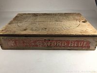 Top view of flat wooden box with faded circular and text branding related to Keen Robinson Oxford Mustard.
