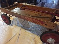 Side view of the wagon showing the red 'WERLICH AIR FLOW' lettering on the wooden side panel with red metal wheels and a reddish pull handle resting on it.