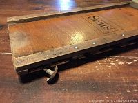 Close-up of the wooden edge with metal reinforcement and caster wheel visible.