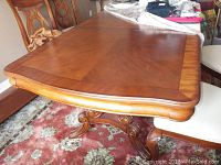 Top view of the wooden rectangular dining table with a polished surface and visible wood grain and decorative border.