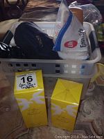 Two bottles of Nina Ricci 'L'Air du Temps' Eau de Toilette in yellow packaging placed next to a gray plastic basket containing a black bag and an open bag of Life Epson Salts.