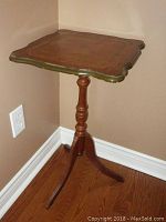 Full view of the small wooden square side table with turned pedestal and tripod legs along wall corner