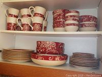 Photo showing ceramic mugs, bowls, and plates neatly arranged on shelves with red and cream floral Marybeth pattern from Pier 1 Imports.