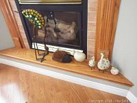 Photo showing the full lot on the wooden hearth with fireplace behind, displaying all figurines and boot scraper.