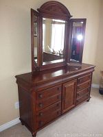 Front and angled views of 7-drawer wooden dresser with a 3-panel mirror on top showing drawer layout and central cabinet door.