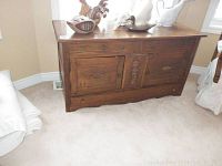 Front view of vintage wooden dresser showing two doors and two drawers with decorative woodwork and brass hardware.