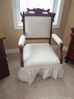 Front view of the vintage Eastlake style chair showing carved top rail, upholstered back, seat with skirt, and armrests.