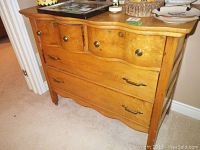 Front view of light wood sideboard highlighting the three large drawers with metal pull handles and four small drawers with round knobs.