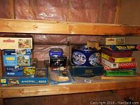 Wide view of shelf showing assortment of board games and jigsaw puzzles including Monopoly, Stock Ticker, Checkers, and various 1000-piece puzzles in colorful boxes.
