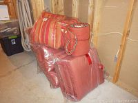 View of assorted wrapped outdoor cushions stacked, including striped and solid color cushions.