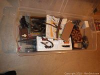 Plastic bin filled with assorted N scale model train track, wiring, manuals, and train packaging.