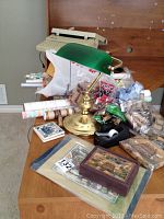 Photo showing Smith Corona electric typewriter placed on desk with green brass lamp, rolls of wrapping paper, coin wrappers and decorative boxes nearby.