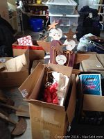 Wooden angel figures visible in cardboard boxes among other packing material and wrapped decorations