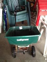 Full view of Golf Green fertilizer spreader showing green plastic hopper with logo and black handle