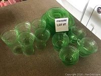 Image showing green depression glassware including glasses, cups, and saucers arranged on a surface