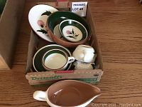 Box containing 3 cups, 3 saucers, 1 bowl, 1 dinner plate, and 1 gravy boat arranged inside showing the green and brown trim with floral pattern.