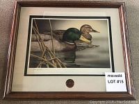 Framed print showing male and female mallard ducks in water with reeds, with a certificate and medallion visible.