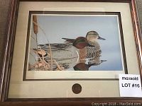 Framed print shows two green-winged ducks on water with reeds, print is signed, in wooden frame with matting.