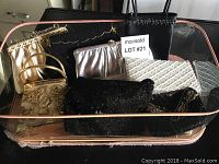 Top view image showing all ten evening purses arranged closely inside a transparent suitcase, showcasing various colors and textures including gold, black, silver, and white with beaded and quilted details.