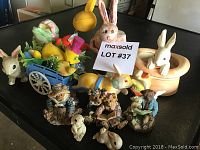 Photo of all ceramic figurines arranged on table: rabbits and bears with a small yellow chick and blue cart