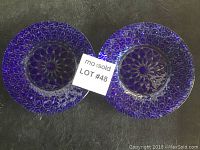 Two deep blue Sydenstricker glass plates with intricate floral and geometric design, placed side by side on a dark surface with lot number card.