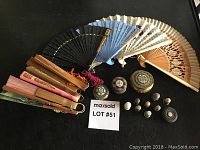 Overall lot layout with hand fans spread out in a fan shape, antique pill boxes and thimbles arranged in front on a black surface with a MaxSold lot number card.