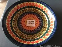 Top view of colorful African decorative ceramic plate with floral and leaf motifs and blue rim.