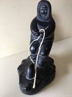 Front view of the black stone carving showing the Indigenous figure holding a rope.