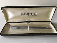 Sheaffer white dot ballpoint pen inside original black metal case with cream satin interior.