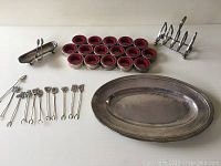 Overview of the entire lot spread out on a white surface showing platter, toast holder, olive tray with tongs, wine stoppers, and olive picks.