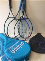 Four tennis racquets visible with two covers, blue Prince cover and black Head cover. The racquets have black and blue grips and distinct racquet heads.