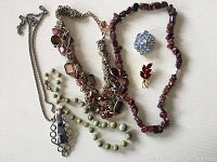 Full view of all four necklaces and two brooches on a flat surface.