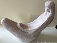 Side view of the sculpture showing the elongated form of the mother figure with the child figure integrated at the base.