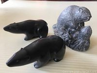 Top side view of two dark polished bear sculptures and one gray stone beaver sculpture.