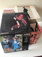 Photo showing four vinyl record jackets: Johnny Mathis Warm, Lou Rawls Live (contains 2 records), ABBA Greatest Hits, and a children's album with two children outdoors.