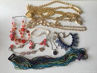 Photo showing an assortment of ladies belts and necklaces including gold-tone chain belts, multi-strand bead necklaces, and costume jewelry with colorful beads and coin pendants.