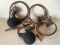 Four antique brass car horns including two with rubber bulbs, showing overall condition and patina
