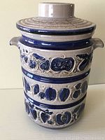 Front view of vintage West German ceramic jar with lid in place showing beige and blue decorative glaze and motifs.