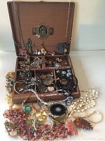 Open wooden jewellery box filled with assorted costume jewellery pieces including necklaces, brooches and bracelets