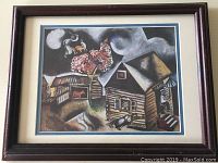 Framed print showing a village scene with houses, tree with blossoms, animals, and a figure under swirling sky