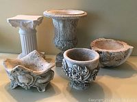 Five outdoor ceramic garden items including urns, vases, and pedestal shown from front angle on a shelf with neutral background.