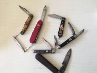 Group photo showing all seven knives of various styles and conditions on a white background