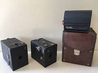 Three cameras: two antique Kodak box cameras and one Polaroid Sun 660 Autofocus camera with case and manual