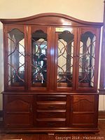 Front view of large mahogany breakfront china closet showing glass doors with decorative muntins and lower cabinet doors and drawers.